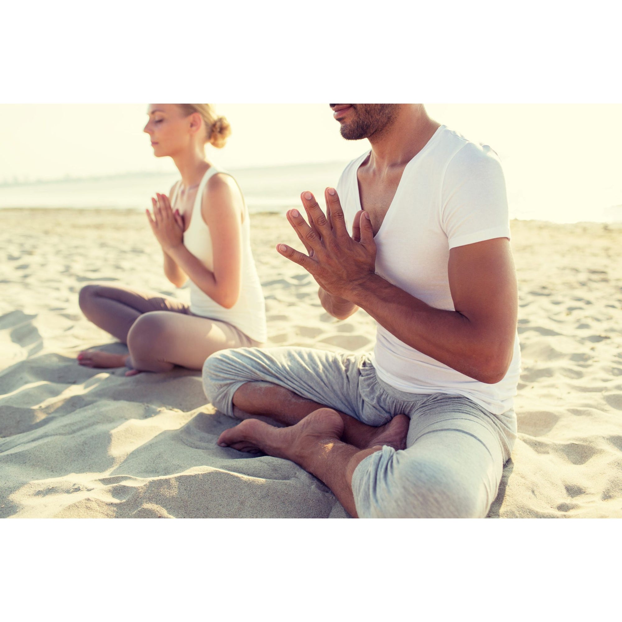 couple on the beach grounding with namaste pose
