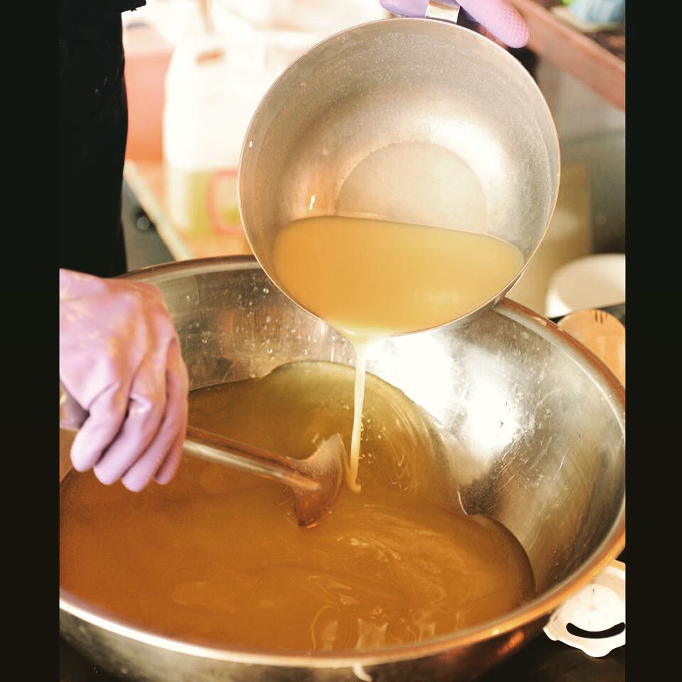 Fresh raw goat milk into organic plant oils in soap shop